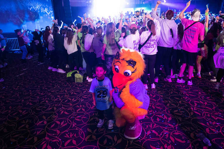 child takes a photo with mascot at dance marathon